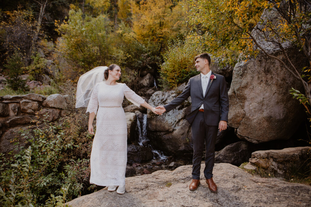 Bride and groom holding hands in front of forest