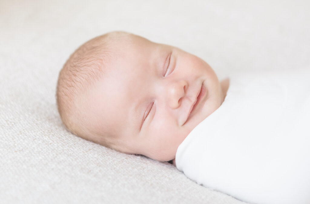 Baby boy smiling while sleeping.